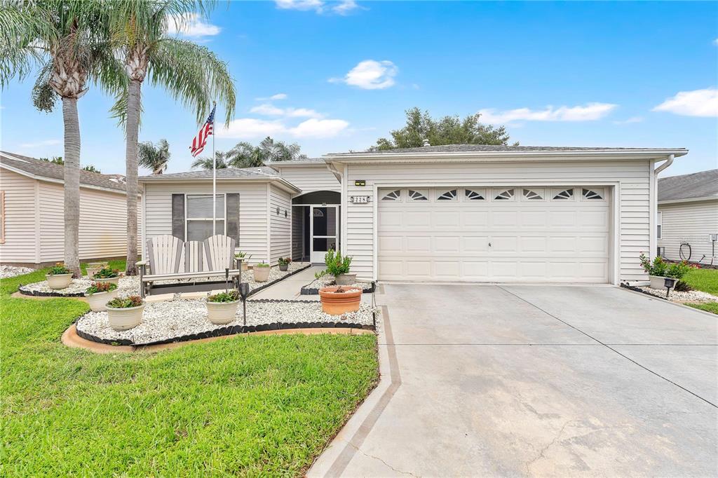A single-story house with light siding, a two-car garage, and a landscaped front yard — 228 GRAND VISTA TRAIL, LEESBURG, FL