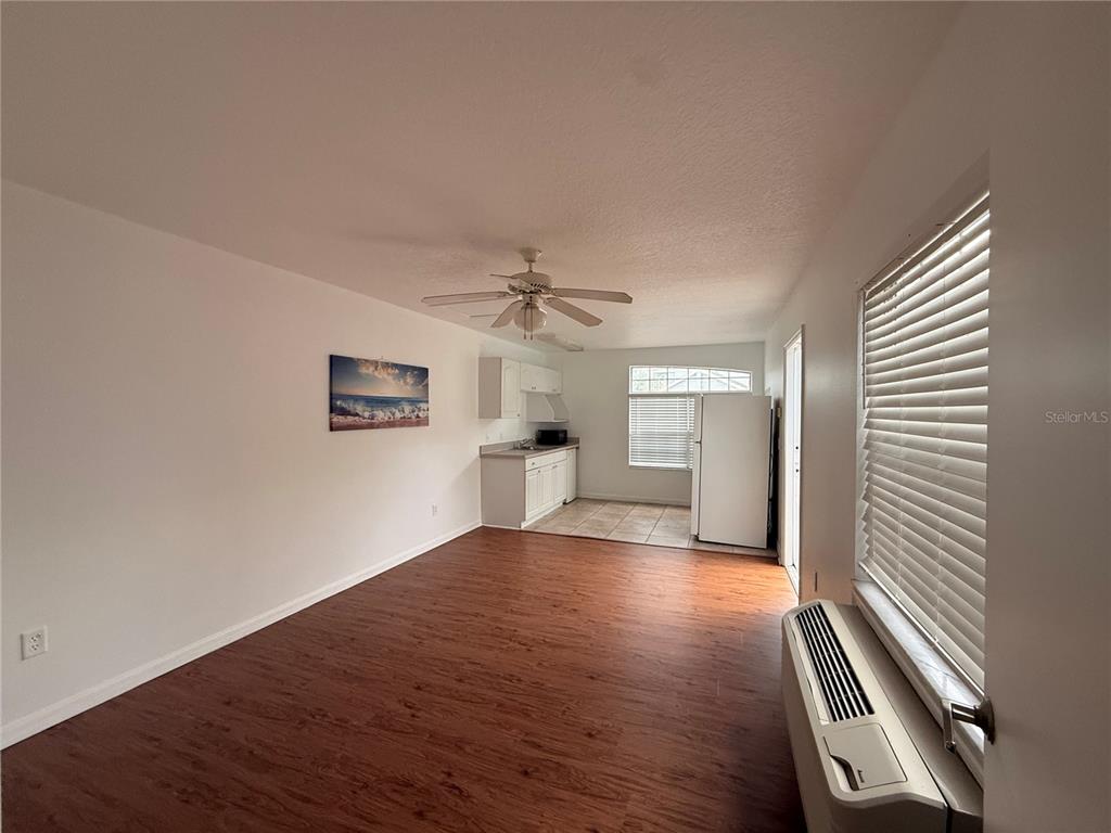 This room features wood-look flooring, a ceiling fan, and an adjacent kitchen area — 527 CARIBBEAN DRIVE UNIT B, DAVENPORT, FL