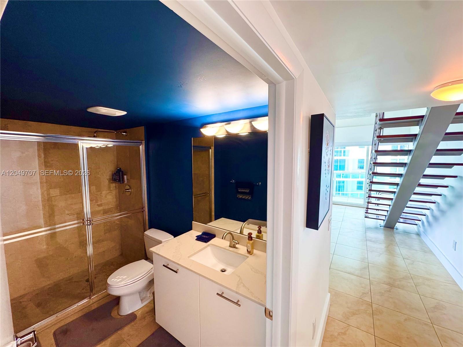 A bathroom with a blue ceiling and shower stall sits adjacent to a staircase — 41 SE 5th St # 1917, Miami FL 33131, MIAMI, FL