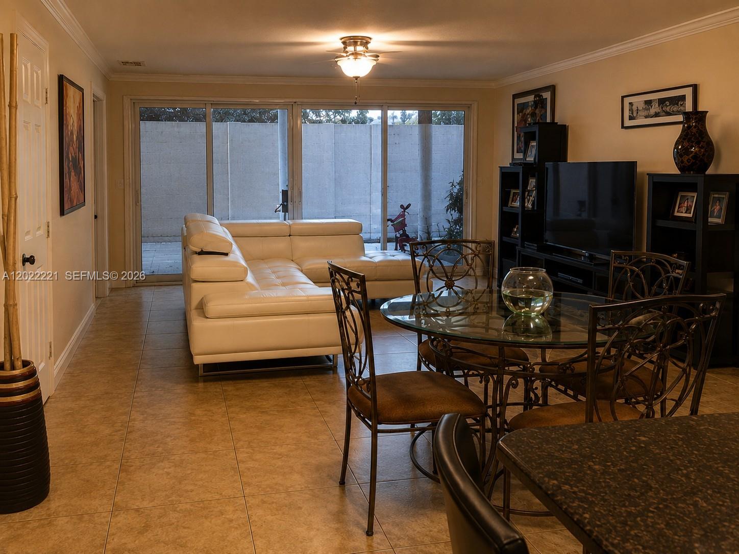 A living and dining area features a white sectional sofa, glass-topped table, and tile flooring — 2839 Taylor St # 8, Hollywood FL 33020, HOLLYWOOD, FL