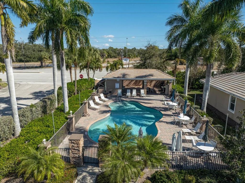 An aerial view of a community swimming pool with lounge chairs and a covered patio — 9815 NOSTALGIA PLACE, ENGLEWOOD, FL