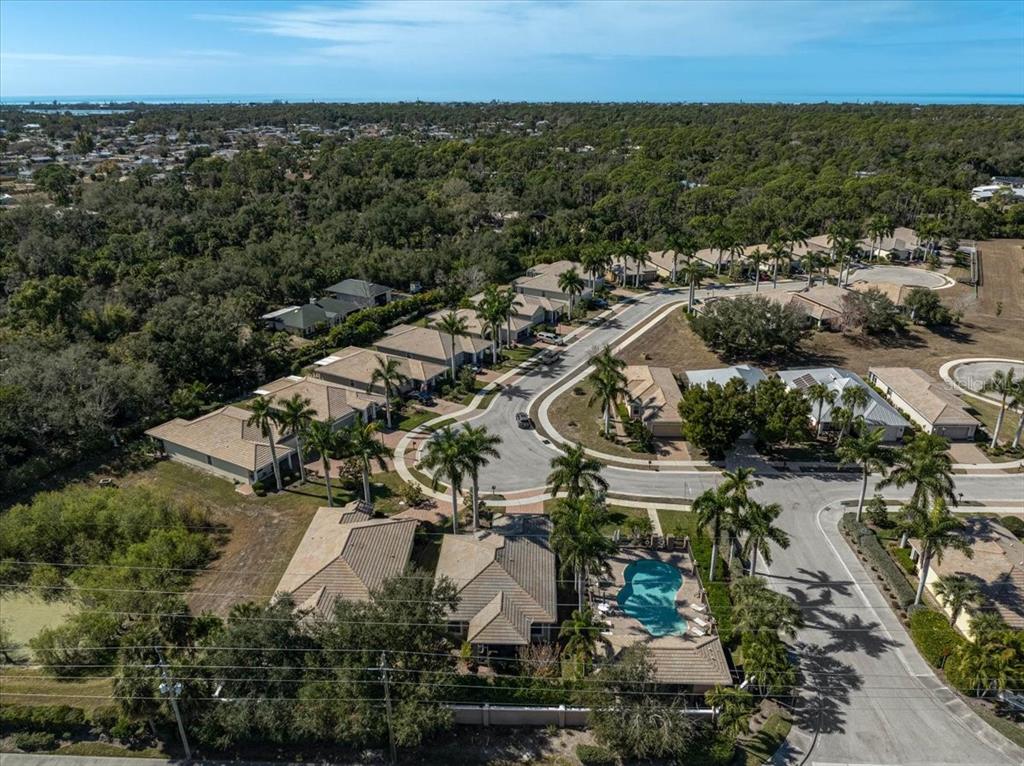 An aerial view shows a suburban neighborhood with houses, palm trees, and a swimming pool — 9815 NOSTALGIA PLACE, ENGLEWOOD, FL