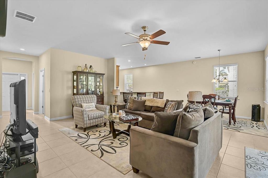 An open-concept living and dining area features tile flooring, a ceiling fan, and neutral walls — 9815 NOSTALGIA PLACE, ENGLEWOOD, FL