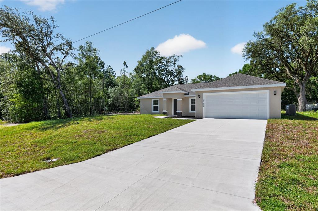 An open-concept kitchen and living area feature light wood-look flooring, white cabinetry, and vaulted ceilings — 22732 SW MARINE BOULEVARD, DUNNELLON, FL