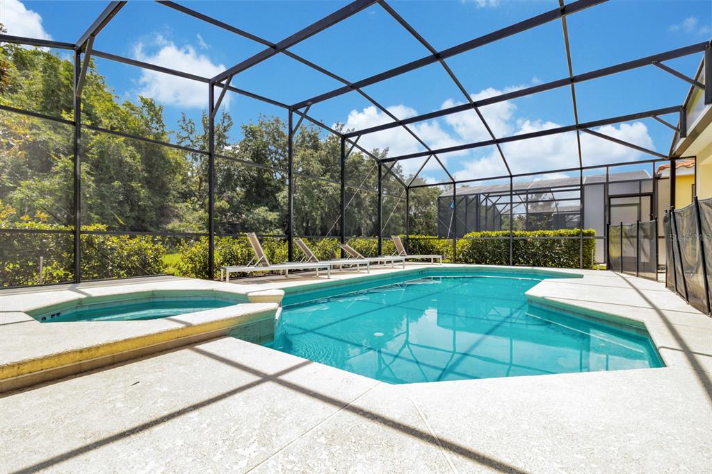 A screened-in swimming pool and hot tub on a concrete patio with lounge chairs — 5248 OAKBOURNE AVENUE, DAVENPORT, FL