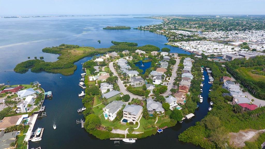 An aerial view shows a waterfront residential community surrounded by mangroves and a large bay — 7107 HAWKS HARBOR CIRCLE, BRADENTON, FL