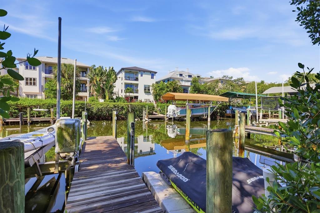 A wooden dock extends into a canal lined with residential buildings and boat slips — 7107 HAWKS HARBOR CIRCLE, BRADENTON, FL