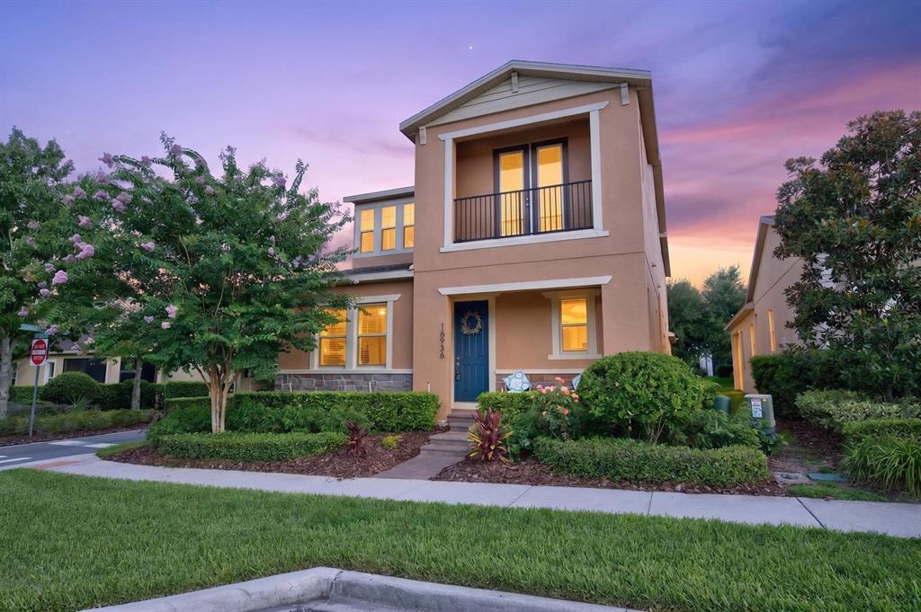 A two-story tan house with a blue front door and a second-story balcony at dusk — 16936 TRADEWIND POINT, WINTER GARDEN, FL
