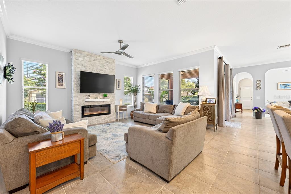 A living room features a stone fireplace, gray sectional sofas, and tile flooring — 16936 TRADEWIND POINT, WINTER GARDEN, FL