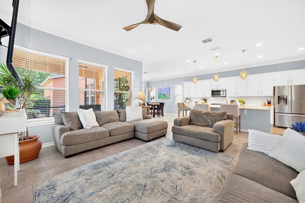 A living room with a sectional sofa, armchair, and an open kitchen with white cabinets — 16936 TRADEWIND POINT, WINTER GARDEN, FL