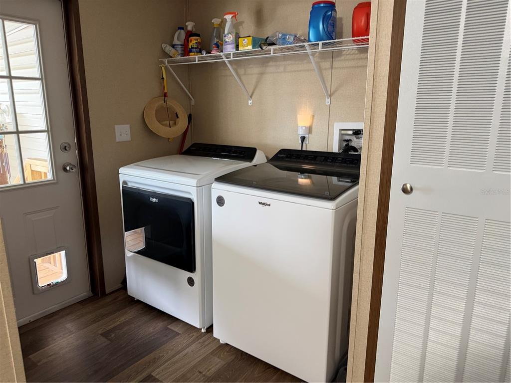 A laundry room features a white washer and dryer, wire shelving, and wood-look flooring — 9209 FONTAINE DRIVE, BROOKSVILLE, FL