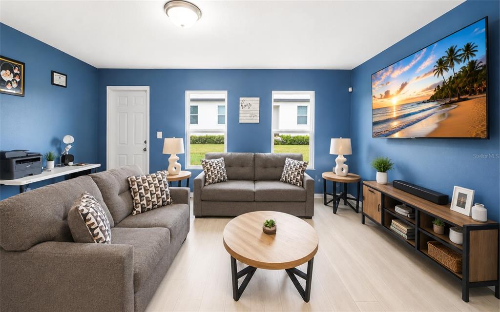 A living room features blue walls, gray sofas, a round coffee table, and a wall-mounted television — 280 FIG COURT, POINCIANA, FL