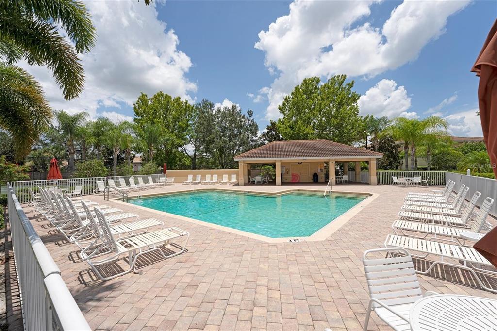 An outdoor swimming pool surrounded by lounge chairs and a covered pavilion under a blue sky — 3770 82ND AVENUE CIRCLE E UNIT 103, SARASOTA, FL