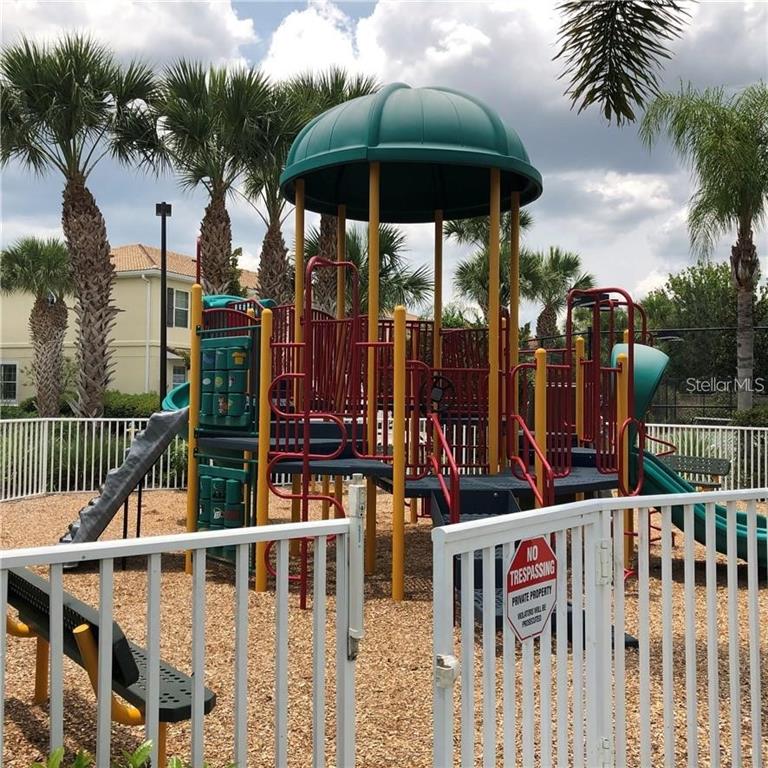 A playground with a green roof, slides, and climbing structures sits inside a fenced area — 3770 82ND AVENUE CIRCLE E UNIT 103, SARASOTA, FL