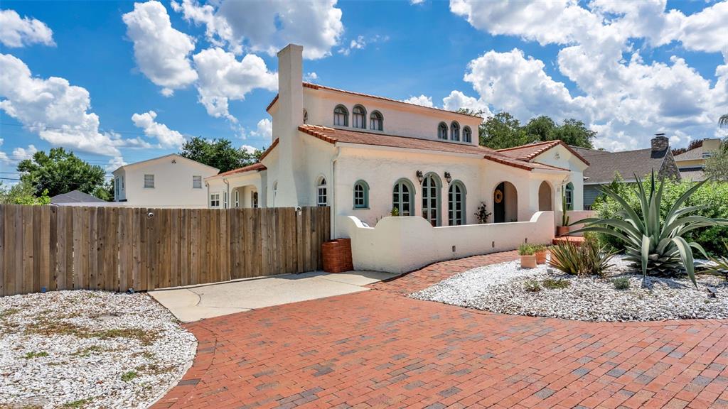 A white stucco house with a red tile roof and brick driveway under a cloudy sky — 743 E EDGEWOOD DRIVE, LAKELAND, FL