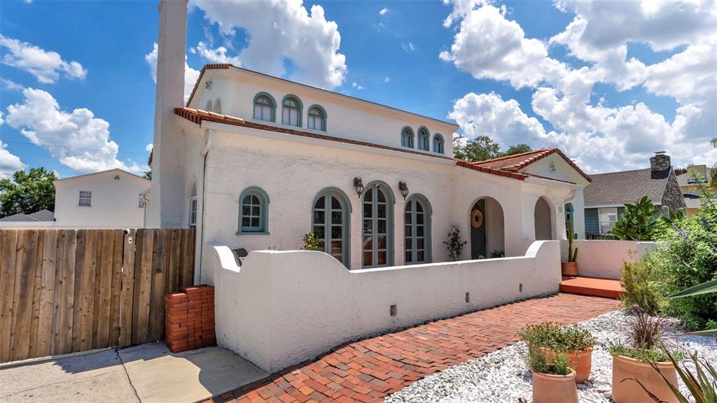A white stucco house with arched windows and a brick walkway under a cloudy sky — 743 E EDGEWOOD DRIVE, LAKELAND, FL