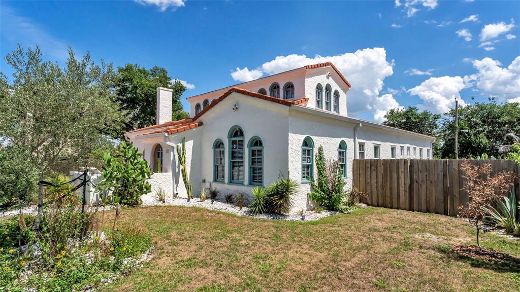A white stucco house with a red tile roof and arched windows sits on grass — 743 E EDGEWOOD DRIVE, LAKELAND, FL