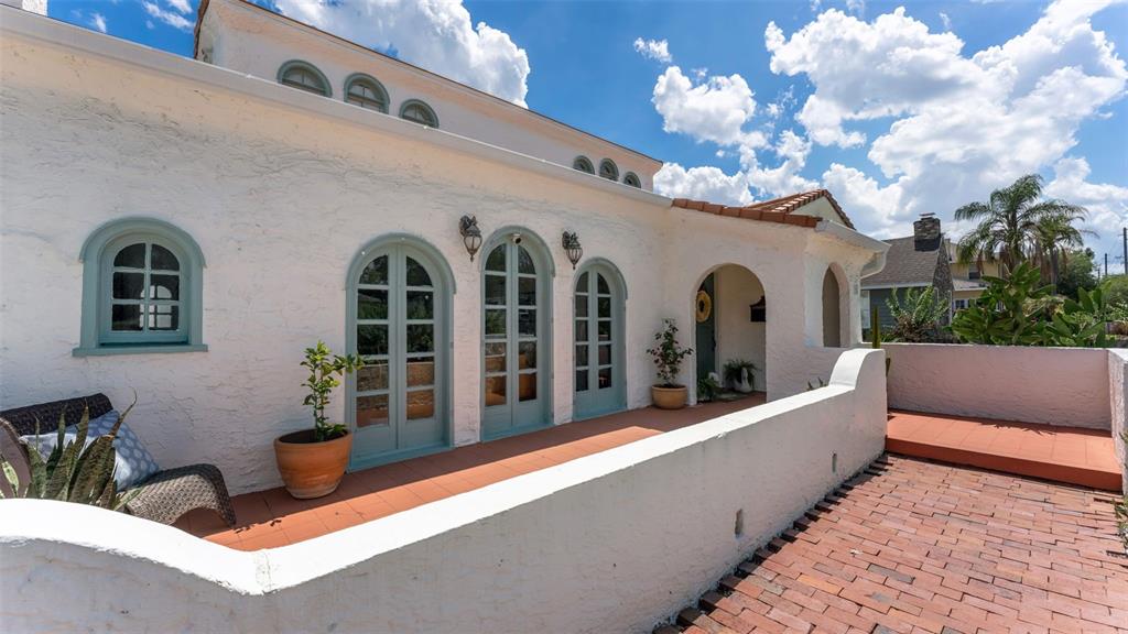 A white stucco house features arched doorways, blue-green trim, and a brick patio — 743 E EDGEWOOD DRIVE, LAKELAND, FL