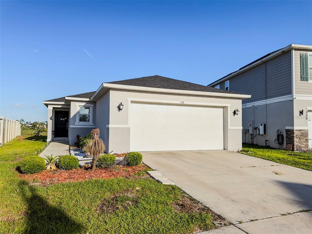 A single-story house with a white garage door, gray exterior, and a small front yard — 334 PRESERVE POINTE BOULEVARD, DAVENPORT, FL