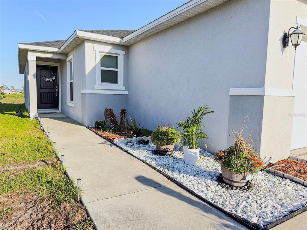 A concrete walkway leads to the front entrance of a house with light-colored exterior walls — 334 PRESERVE POINTE BOULEVARD, DAVENPORT, FL