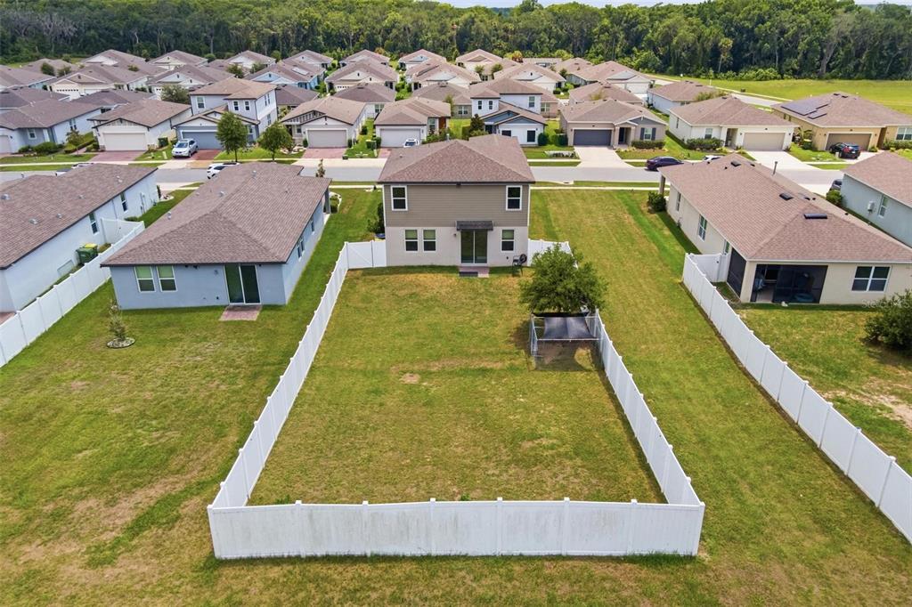 An aerial view shows a two-story house with a fenced backyard in a suburban neighborhood — 29460 CASPIAN STREET, LEESBURG, FL