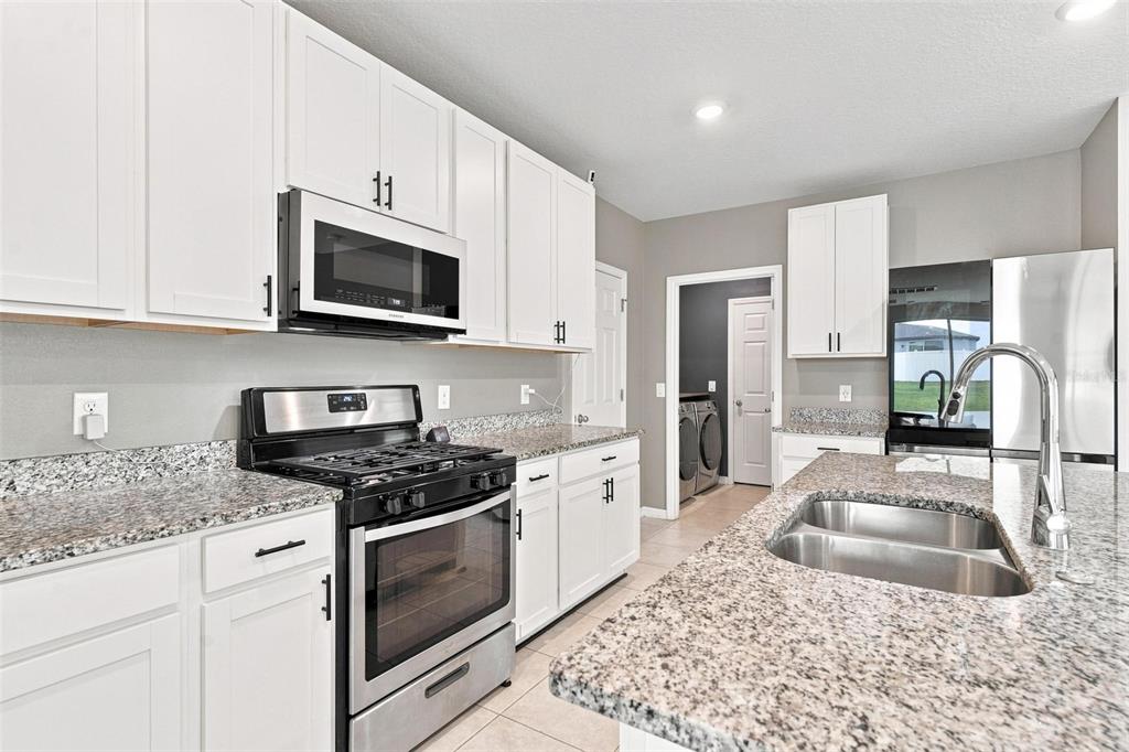 A kitchen features white cabinets, granite countertops, stainless steel appliances, and a double-basin sink — 29460 CASPIAN STREET, LEESBURG, FL