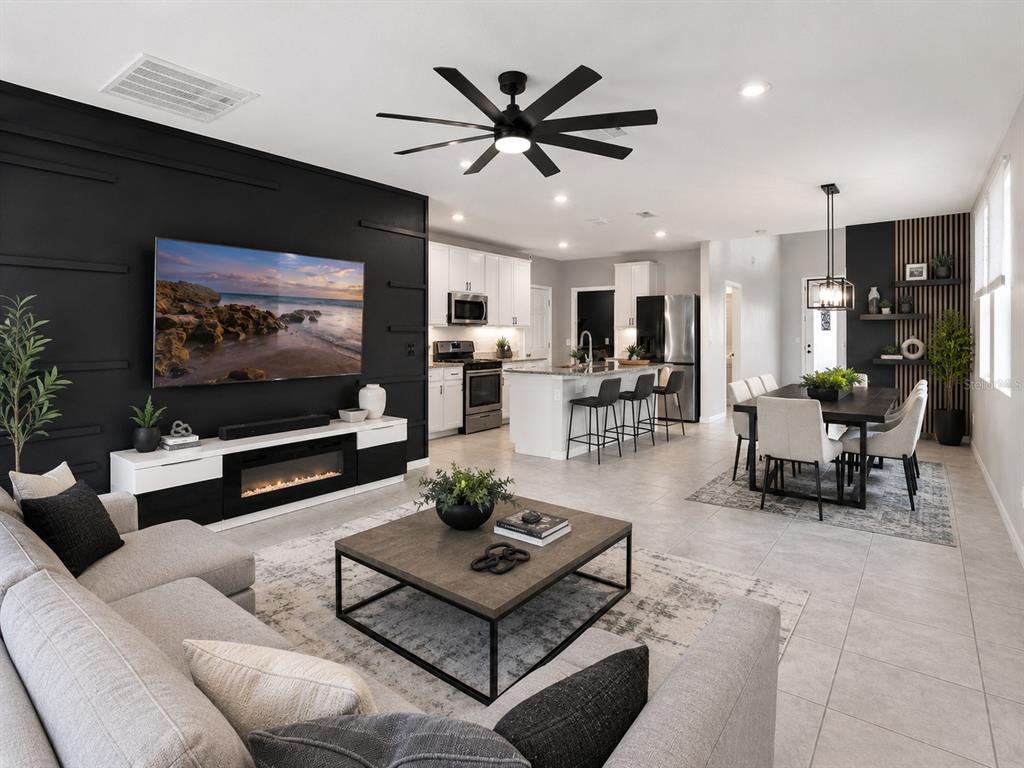 An open-concept living and dining area features a black accent wall, modern furniture, and tile flooring — 29460 CASPIAN STREET, LEESBURG, FL