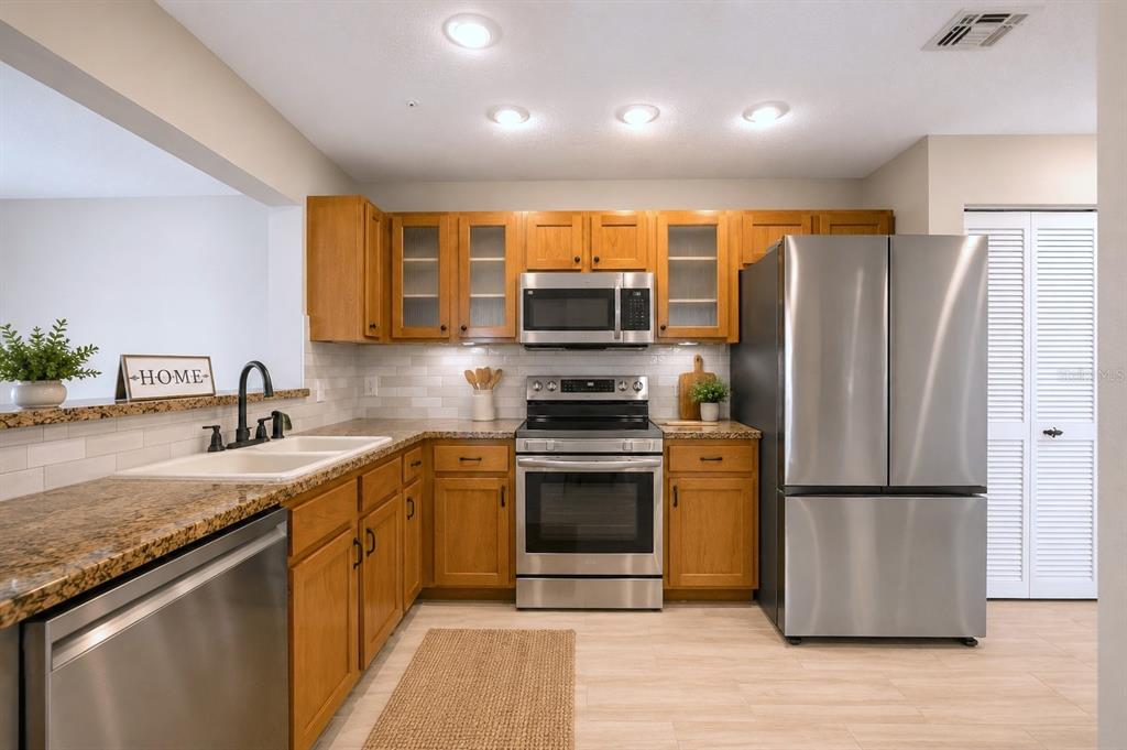 A kitchen features wood cabinets, granite countertops, stainless steel appliances, and a white tile backsplash — 641 MAPLE OAK CIRCLE UNIT 101, ALTAMONTE SPRINGS, FL