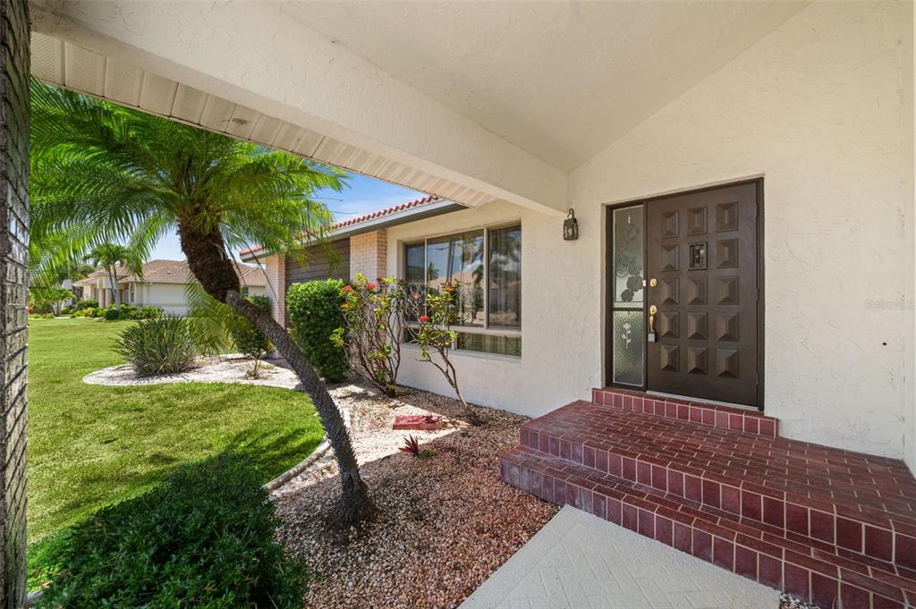 A covered entryway with brick steps leads to a dark brown front door with glass panels — 3330 TRIPOLI BOULEVARD, PUNTA GORDA, FL