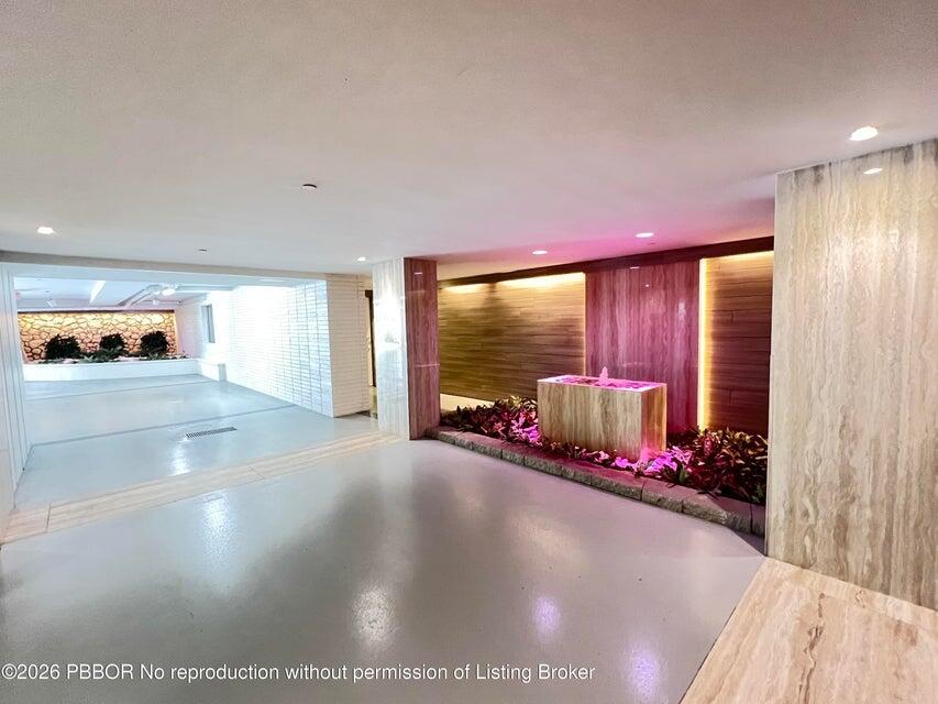 A modern indoor lobby features a stone water fountain, wood-paneled walls, and recessed lighting — 2773 S Ocean Boulevard # 414, Palm Beach FL 33480, PALM BEACH, FL