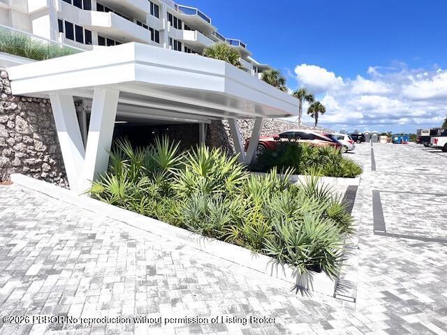 A white modern carport structure sits above a landscaped garden bed in a paved parking area — 2773 S Ocean Boulevard # 414, Palm Beach FL 33480, PALM BEACH, FL