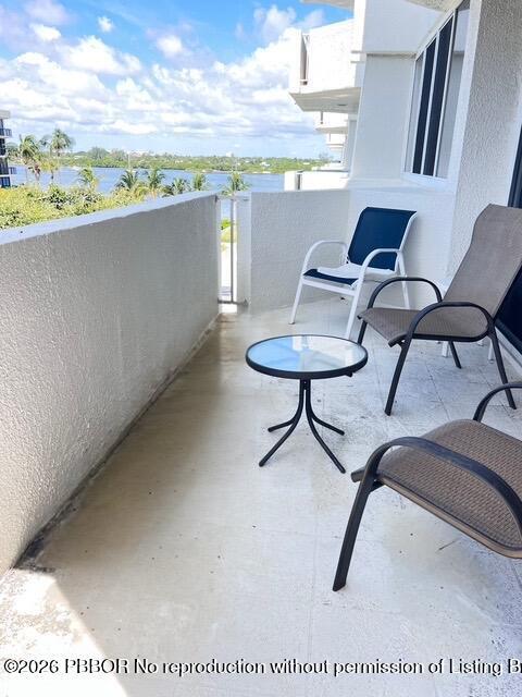 A balcony features a small round table and three chairs overlooking a waterfront view — 2773 S Ocean Boulevard # 414, Palm Beach FL 33480, PALM BEACH, FL