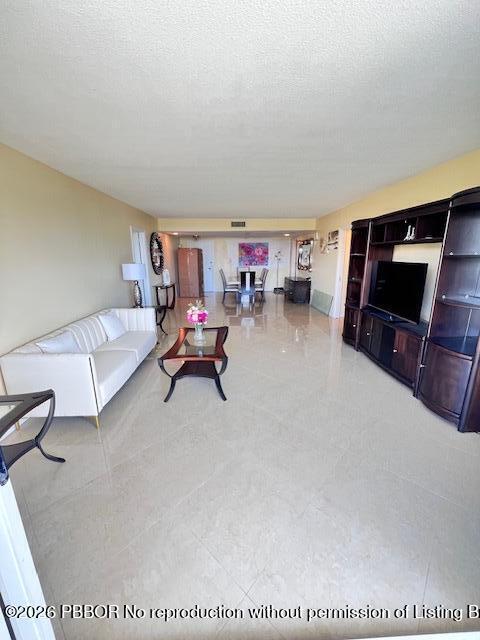A spacious living room features light tile flooring, a white sofa, and a dark entertainment center — 2773 S Ocean Boulevard # 414, Palm Beach FL 33480, PALM BEACH, FL