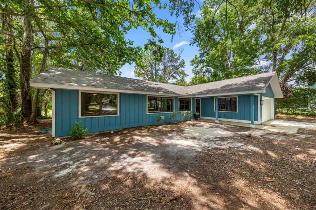 A blue, single-story house with board-and-batten siding sits in a wooded yard — 2907 S SKYLINE DRIVE, INVERNESS, FL