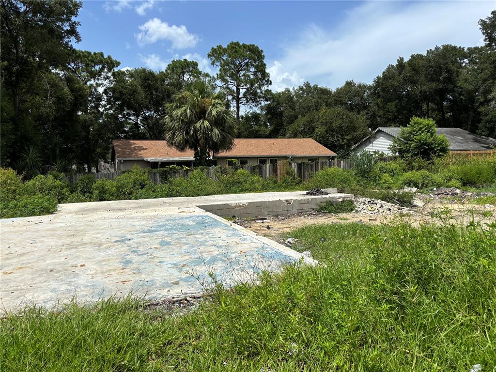 A concrete slab foundation sits in a grassy lot with trees and houses in the background — 25815 EXMOOR DRIVE, SORRENTO, FL