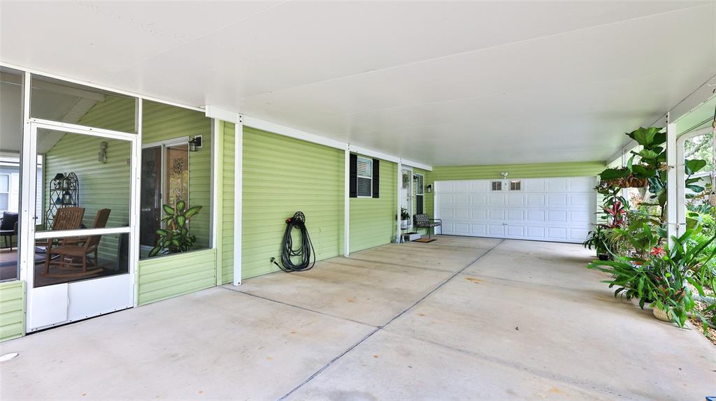 A covered carport with light green siding, a concrete floor, and a white garage door — 380 MARSH LANDING LOOP, OAK HILL, FL