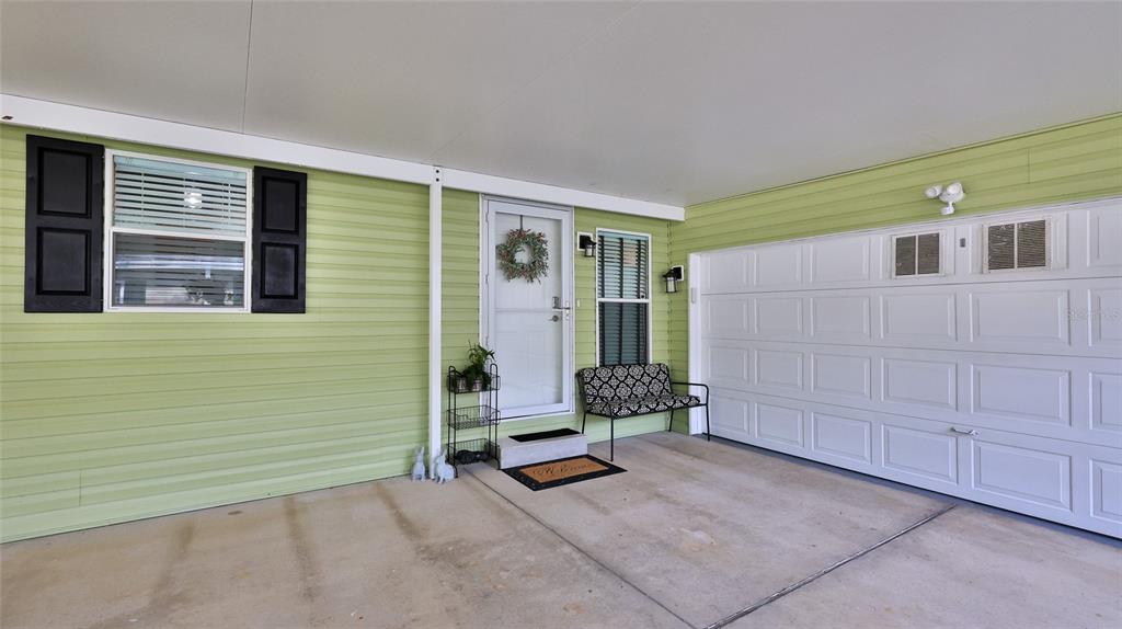 A light green house exterior features a covered carport, a white garage door, and a door — 380 MARSH LANDING LOOP, OAK HILL, FL