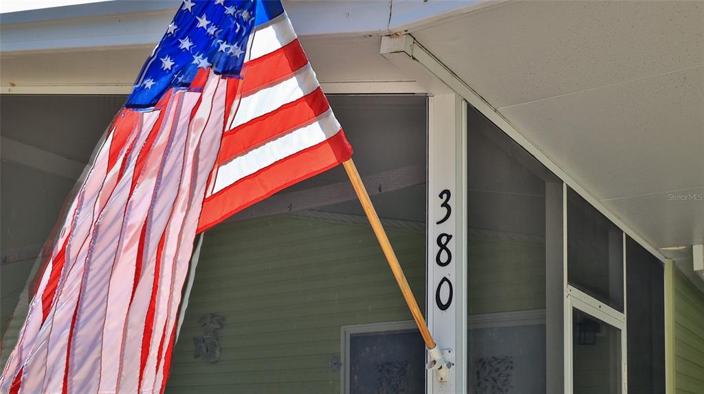 An American flag is mounted on a post next to the house number 380 — 380 MARSH LANDING LOOP, OAK HILL, FL