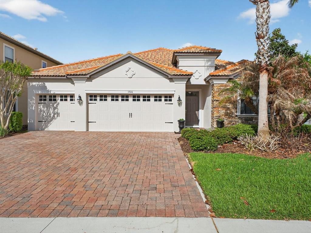 A single-story house with a brick paver driveway, three-car garage, and a tiled roof — 1300 GLENEAGLES LANE, DAVENPORT, FL