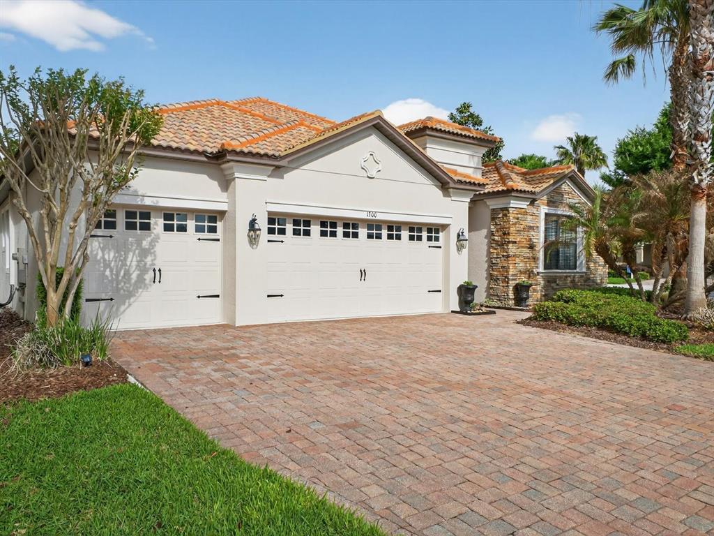 A single-story house with a brick paver driveway, three-car garage, and stone facade — 1300 GLENEAGLES LANE, DAVENPORT, FL