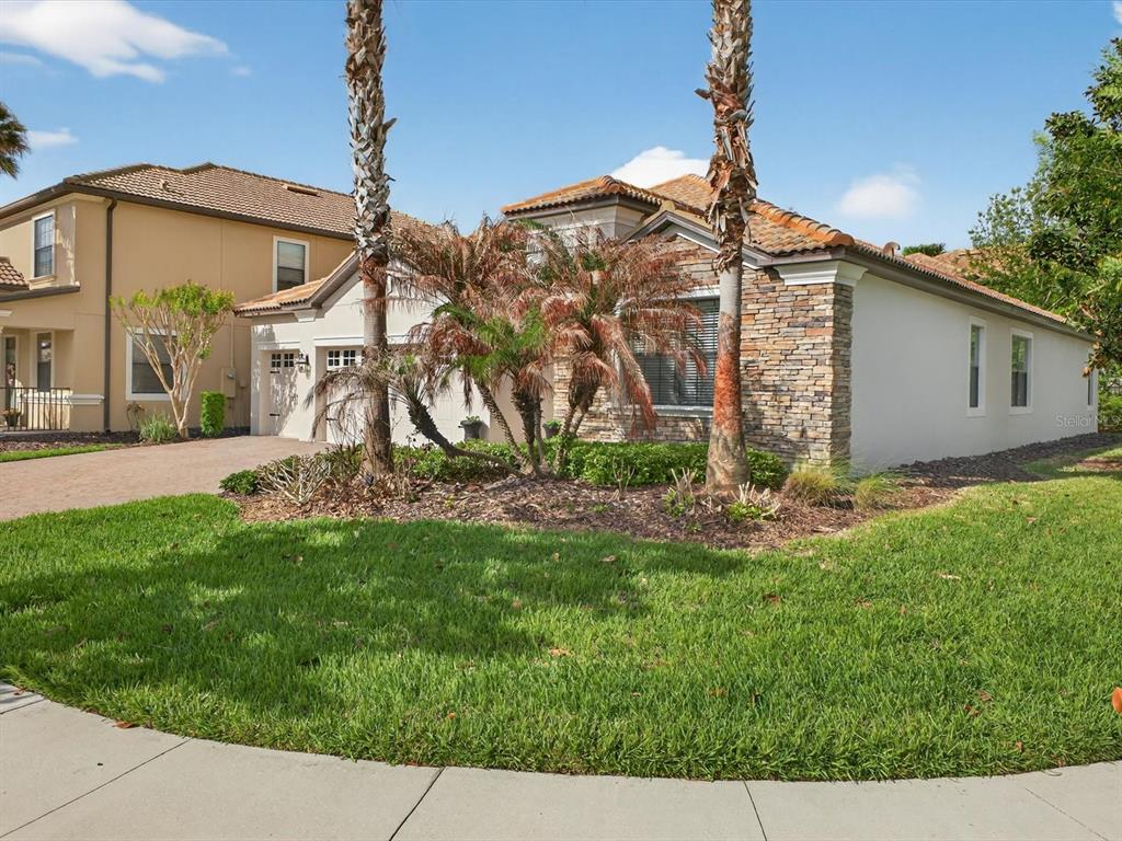 A single-story house with a stone facade, palm trees, and a green lawn — 1300 GLENEAGLES LANE, DAVENPORT, FL