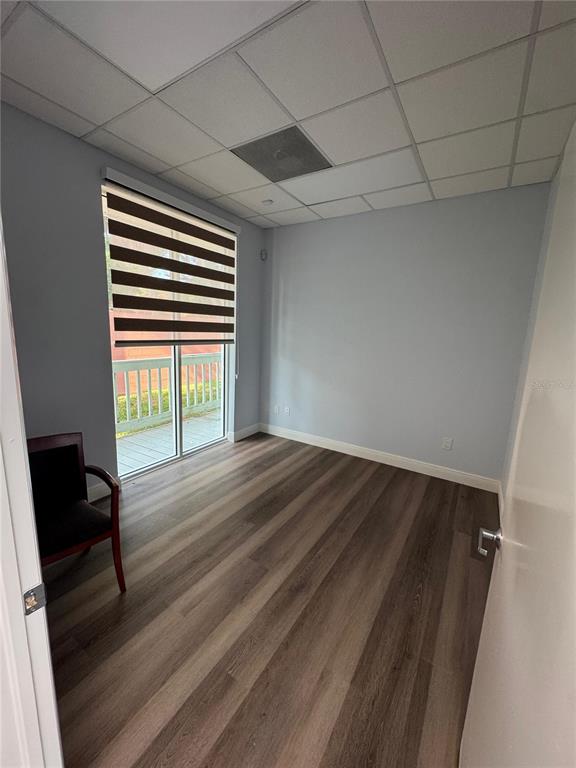 An empty office with light blue walls, wood-look flooring, a drop ceiling, and a sliding door — 2708 W VIRGINIA AVENUE, TAMPA, FL