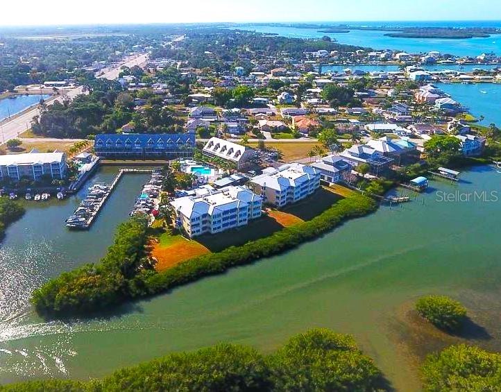 An aerial view shows waterfront condominium buildings with a private boat dock and marina — 2424 PLACIDA ROAD UNIT C104, ENGLEWOOD, FL