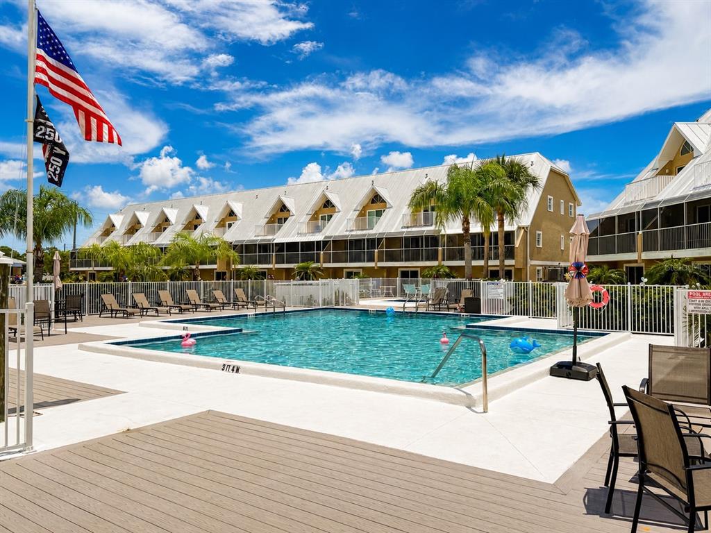 A swimming pool sits in front of a multi-story building with a metal roof — 2424 PLACIDA ROAD UNIT C104, ENGLEWOOD, FL