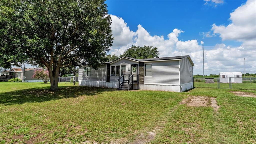 A single-story manufactured home with light gray siding sits on a grassy lot — 1329 ASHLEE COURT, AUBURNDALE, FL