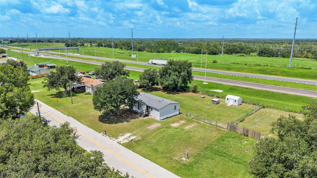 An aerial view shows a single-story house with a fenced yard near a highway — 1329 ASHLEE COURT, AUBURNDALE, FL
