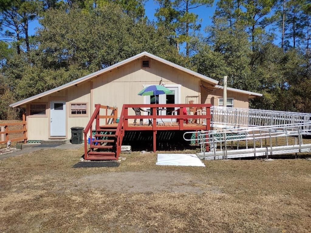 A single-story house with a wooden deck, stairs, and a metal wheelchair ramp — 1916 LAUREL AVENUE, BUNNELL, FL