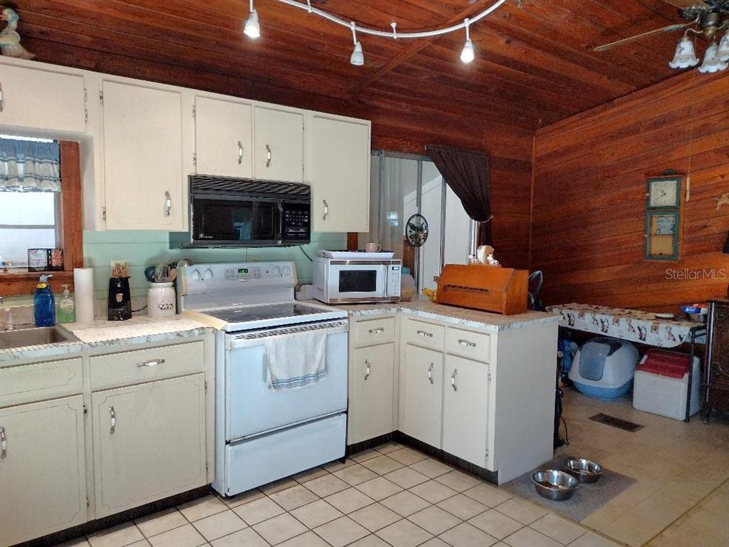 A kitchen with white cabinets, a white stove, and wood-paneled walls and ceiling — 1916 LAUREL AVENUE, BUNNELL, FL