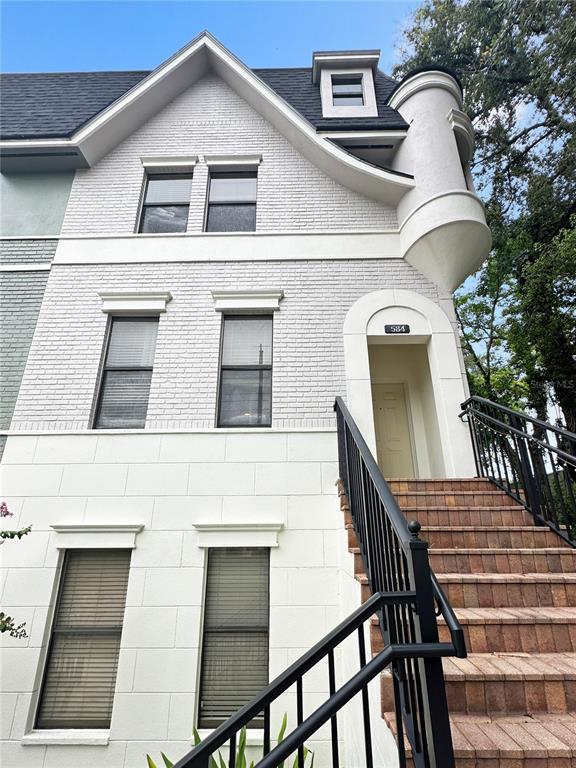 A white brick townhouse exterior features a turret, arched entryway, and stone steps — 584 COPLEY LANE, ORLANDO, FL