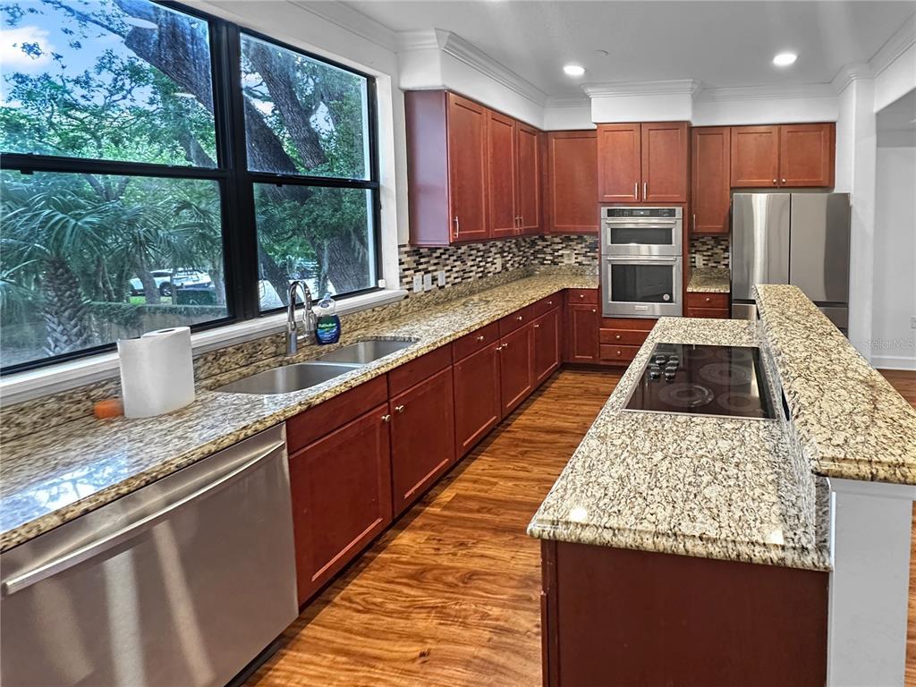 A kitchen features wood cabinets, granite countertops, stainless steel appliances, and a large window — 584 COPLEY LANE, ORLANDO, FL